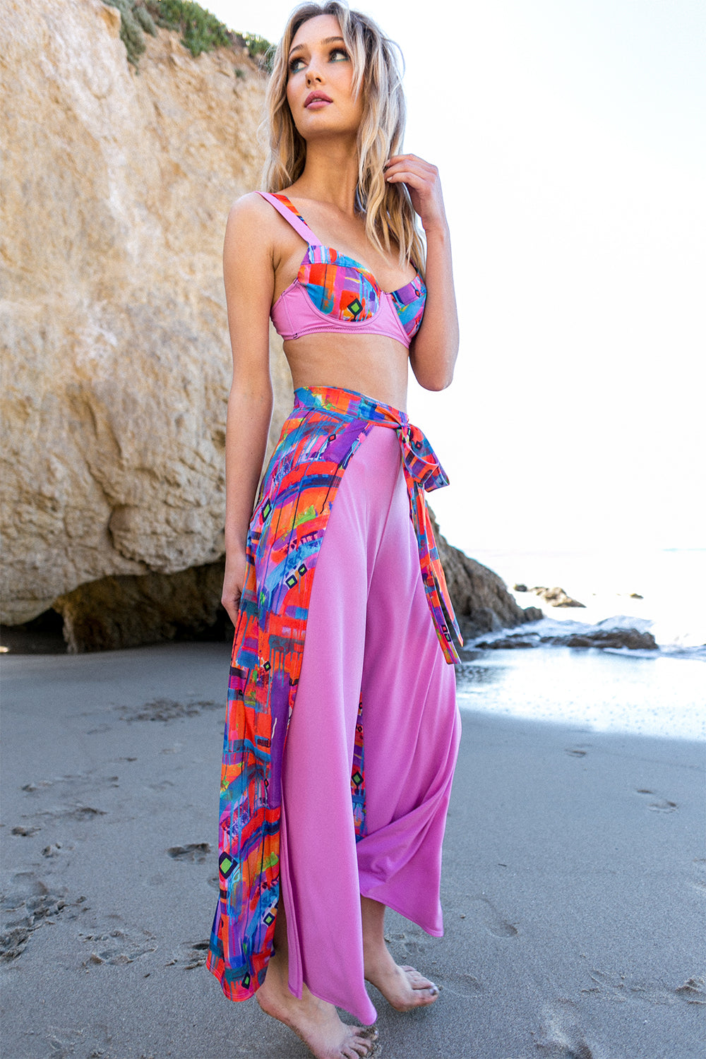 woman on beach wearing pink wrap pant neon